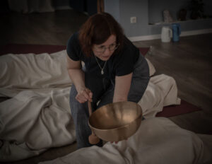 Valentina hält bei einem Breathwork-Retreat eine Klangschale neben einer liegenden Person.